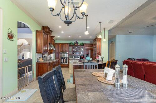 dining area with an inviting chandelier, crown molding, and light tile patterned flooring