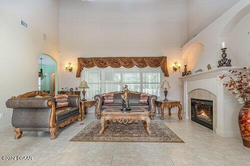 living area with a fireplace, a high ceiling, and light tile patterned floors