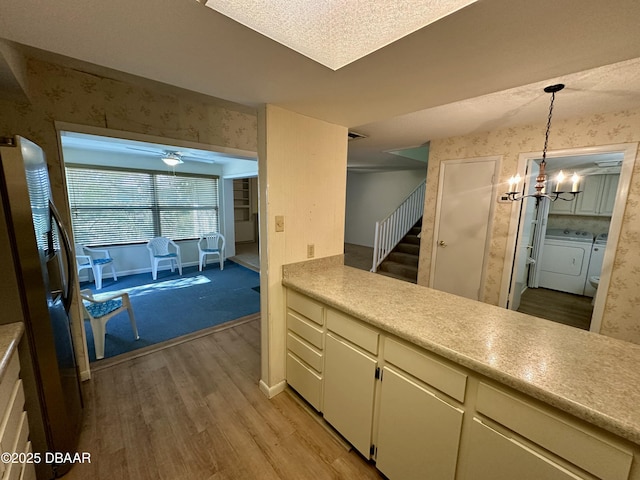 4150 S Atlantic Ave Unit 102B, New Smyrna Beach, FL 32169 - kitchen featuring washer and dryer, light wood finished floors, wallpapered walls, light countertops, and hanging light fixtures