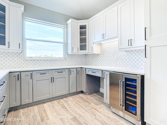 kitchen with gray cabinets, tasteful backsplash, white cabinets, wine cooler, and light wood-type flooring