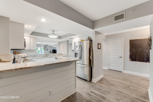 kitchen featuring white cabinetry, light stone counters, kitchen peninsula, stainless steel fridge, and light wood-type flooring