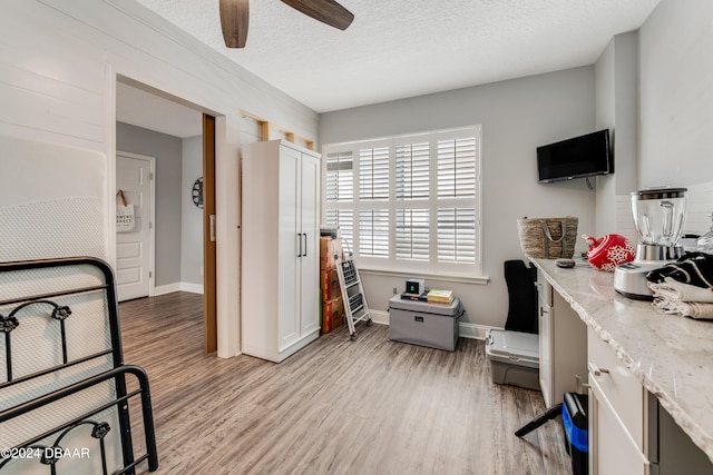 office space with ceiling fan, a textured ceiling, and light wood-type flooring