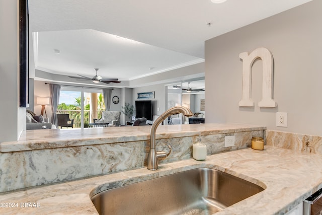 kitchen with light stone countertops, ceiling fan, sink, and crown molding