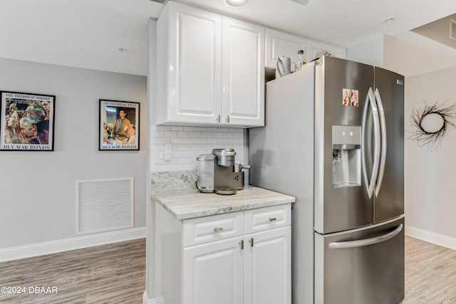 kitchen featuring white cabinets, stainless steel fridge with ice dispenser, light hardwood / wood-style flooring, and tasteful backsplash