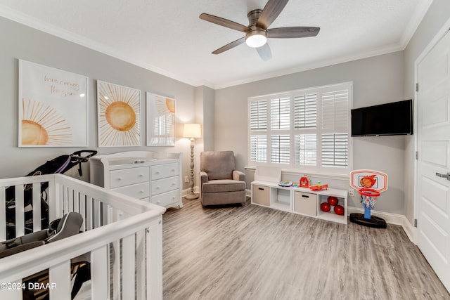 bedroom with hardwood / wood-style flooring, ornamental molding, ceiling fan, a textured ceiling, and a crib