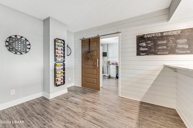 empty room featuring a barn door, hardwood / wood-style flooring, and wooden walls