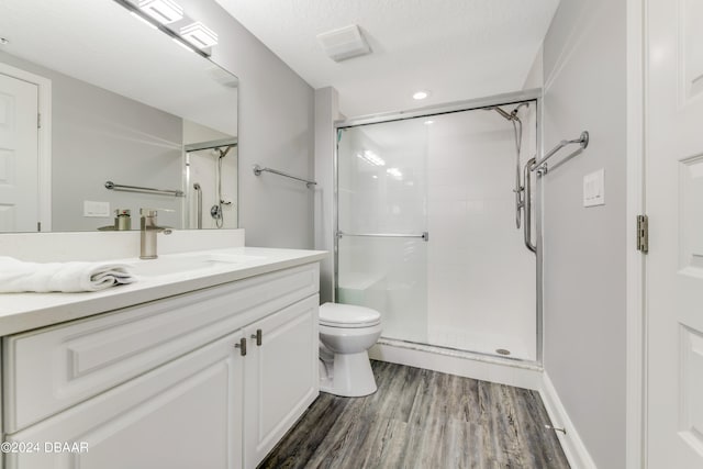 bathroom featuring toilet, a textured ceiling, hardwood / wood-style flooring, an enclosed shower, and vanity