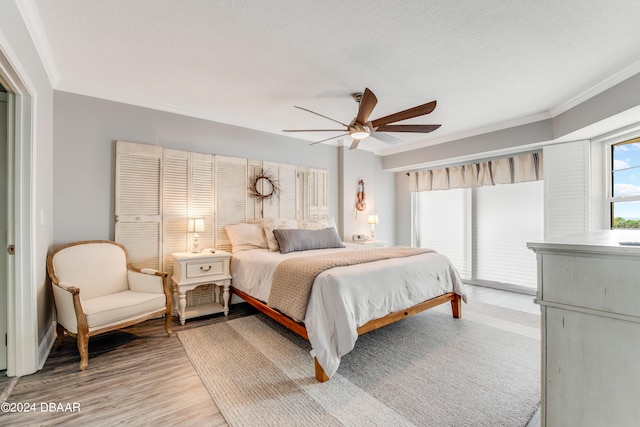 bedroom featuring hardwood / wood-style flooring, a textured ceiling, ornamental molding, and ceiling fan