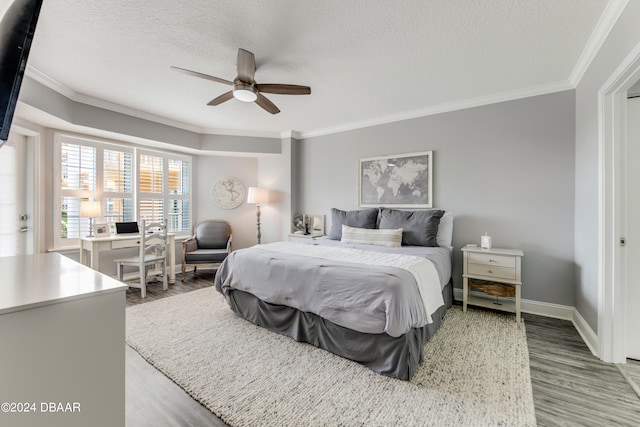 bedroom with a textured ceiling, ornamental molding, wood-type flooring, and ceiling fan