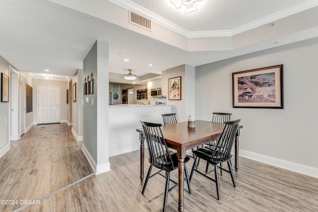 dining area featuring a textured ceiling, crown molding, and light hardwood / wood-style flooring