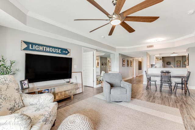 living room with hardwood / wood-style floors, ceiling fan, and crown molding