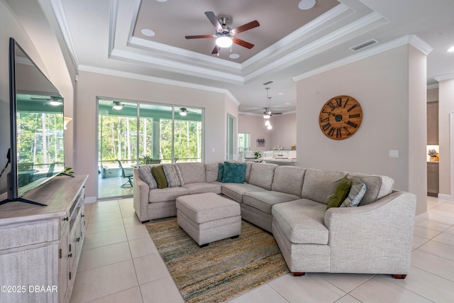 living area featuring ceiling fan, a raised ceiling, light tile patterned floors, and ornamental molding