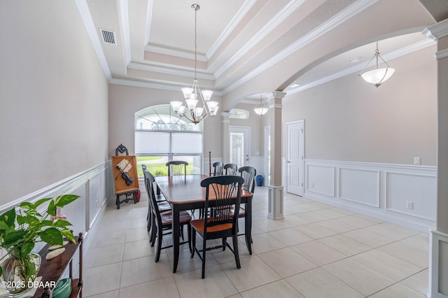 dining area featuring decorative columns, arched walkways, a decorative wall, a chandelier, and ornamental molding