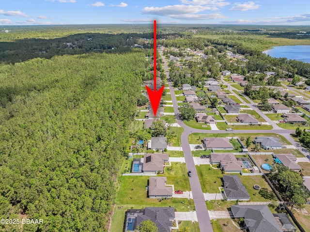 view of property location featuring a heavily wooded area, a nearby body of water, and nearby suburban area