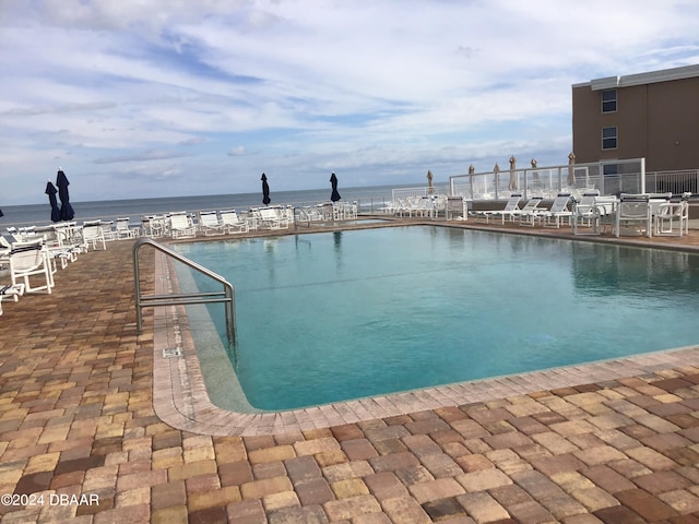 view of swimming pool featuring a water view and a patio area