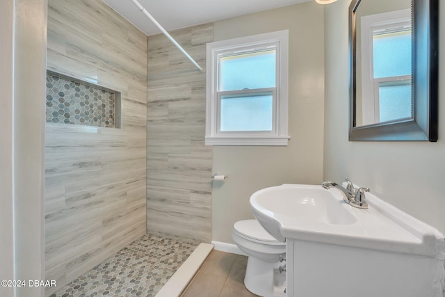 bathroom with toilet, vanity, tile patterned flooring, and tiled shower