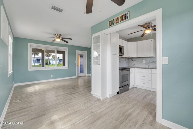 kitchen featuring stainless steel appliances, light stone counters, tasteful backsplash, white cabinets, and light wood-type flooring