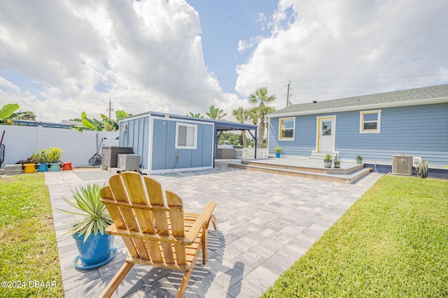 rear view of house with cooling unit, a storage unit, a lawn, and a patio area