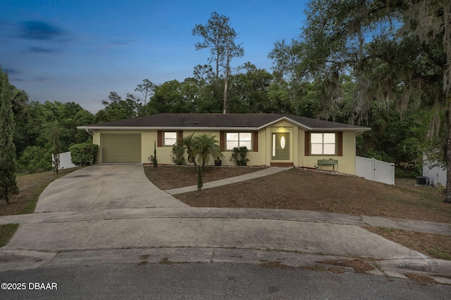 ranch-style home featuring driveway, an attached garage, stucco siding, and fence