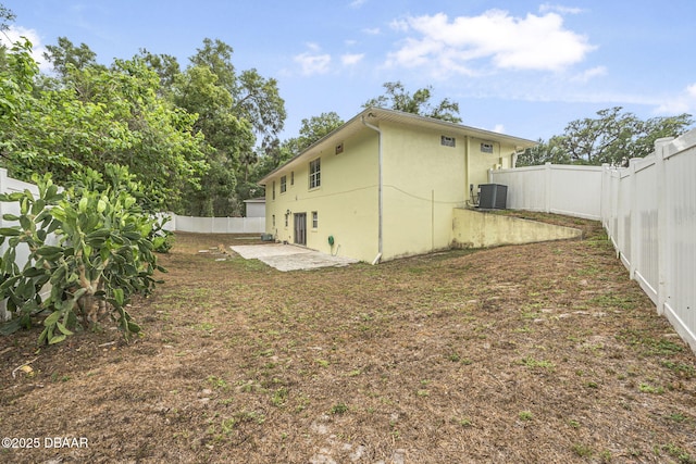 rear view of house featuring a patio area, a fenced backyard, stucco siding, and central AC unit
