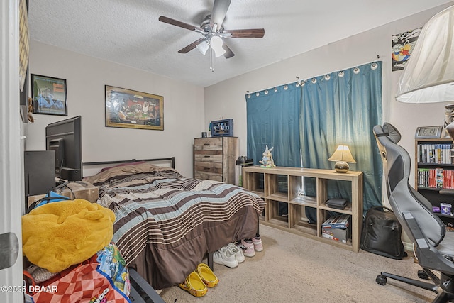 bedroom featuring a desk, carpet, a textured ceiling, and a ceiling fan