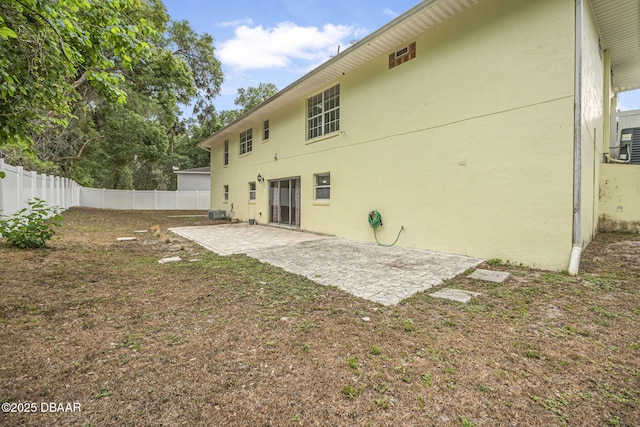 rear view of property featuring a patio area, fence, and stucco siding