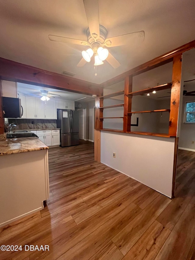 kitchen featuring light stone counters, white cabinets, hardwood / wood-style floors, ceiling fan, and stainless steel fridge