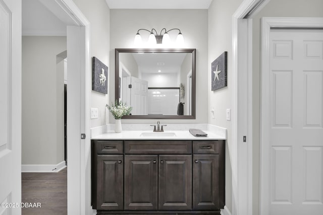 bathroom featuring vanity, wood finished floors, baseboards, and a shower with door