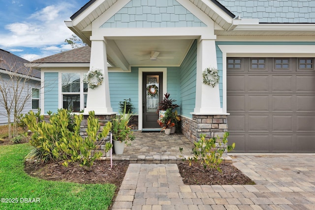 property entrance with covered porch, a shingled roof, ceiling fan, a garage, and stone siding