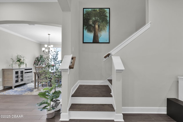 stairs featuring crown molding, wood finished floors, arched walkways, and baseboards