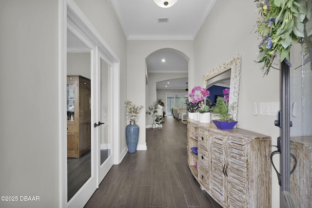 hall with visible vents, ornamental molding, arched walkways, french doors, and dark wood-style floors