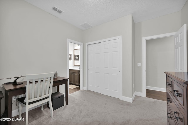 home office featuring carpet, baseboards, visible vents, and a textured ceiling