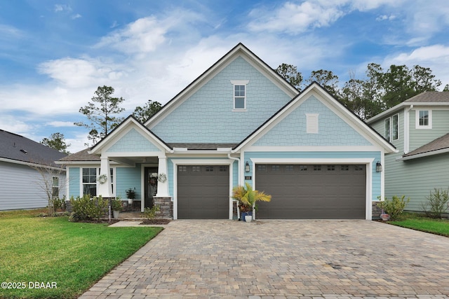 craftsman-style home with decorative driveway, a garage, and a front yard