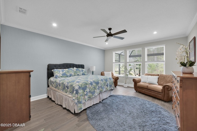 bedroom featuring visible vents, crown molding, baseboards, and wood finished floors