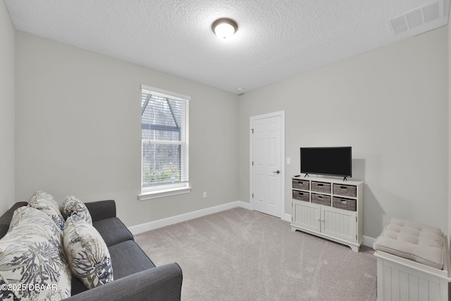 living room with a textured ceiling, light colored carpet, visible vents, and baseboards