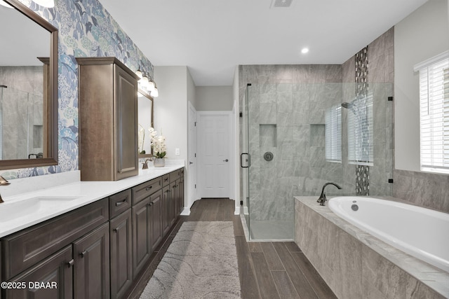 full bath featuring a stall shower, a sink, wood finished floors, double vanity, and a bath