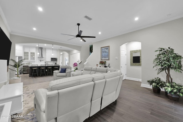 living area with visible vents, crown molding, dark wood-style floors, recessed lighting, and arched walkways