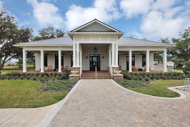 view of front of house with a ceiling fan, a standing seam roof, a porch, a front lawn, and metal roof