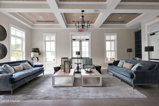 living area featuring built in features, coffered ceiling, an inviting chandelier, and wood finished floors