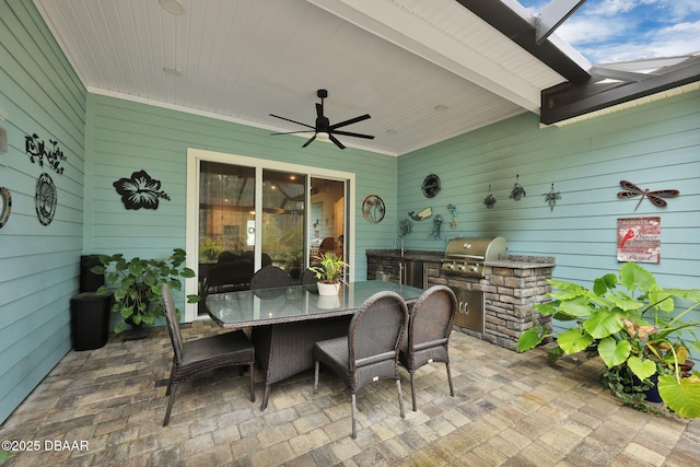 view of patio with a ceiling fan, grilling area, glass enclosure, exterior kitchen, and outdoor dining area