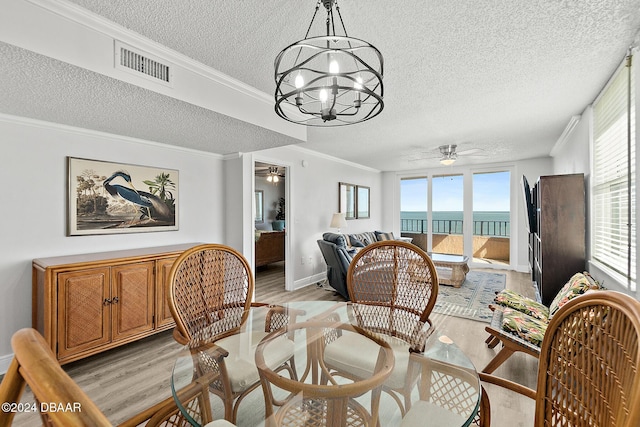 3370 Ocean Shore Blvd Unit 404B, Ormond Beach, FL 32176 - dining space with a textured ceiling, light wood-type flooring, a ceiling fan, a chandelier, and crown molding