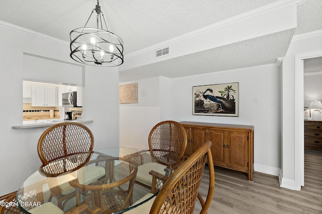 3370 Ocean Shore Blvd Unit 404B, Ormond Beach, FL 32176 - dining space with a textured ceiling, a chandelier, light wood-style floors, ornamental molding, and baseboards