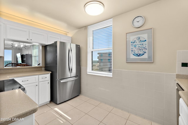 kitchen featuring light tile patterned flooring, white cabinetry, stainless steel appliances, and tile walls