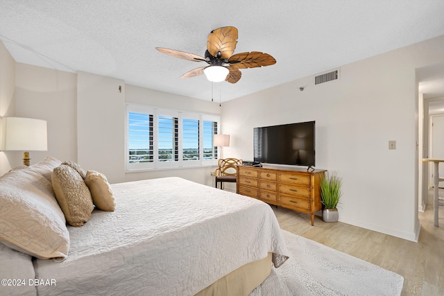 bedroom with ceiling fan, a textured ceiling, and light wood-type flooring