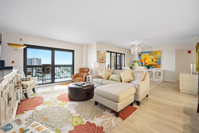 living room with an inviting chandelier, a textured ceiling, and light hardwood / wood-style flooring