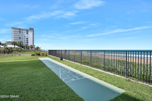 view of property's community featuring a view of the beach, a water view, and a lawn