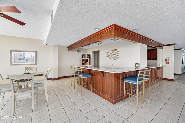 kitchen with kitchen peninsula, a textured ceiling, light tile patterned floors, and ceiling fan