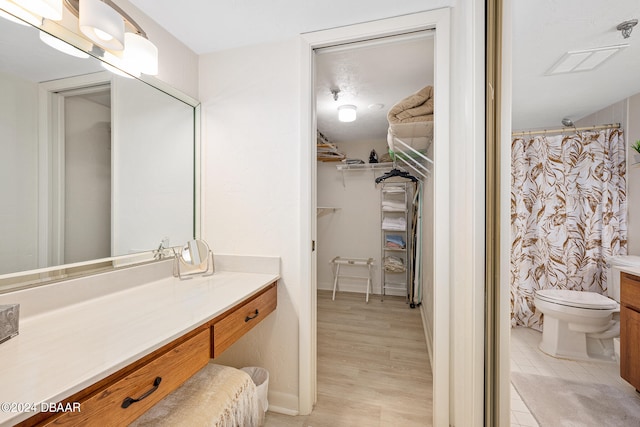 bathroom featuring walk in shower, wood-type flooring, vanity, and toilet