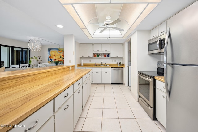 kitchen with appliances with stainless steel finishes, light tile patterned floors, sink, white cabinets, and ceiling fan