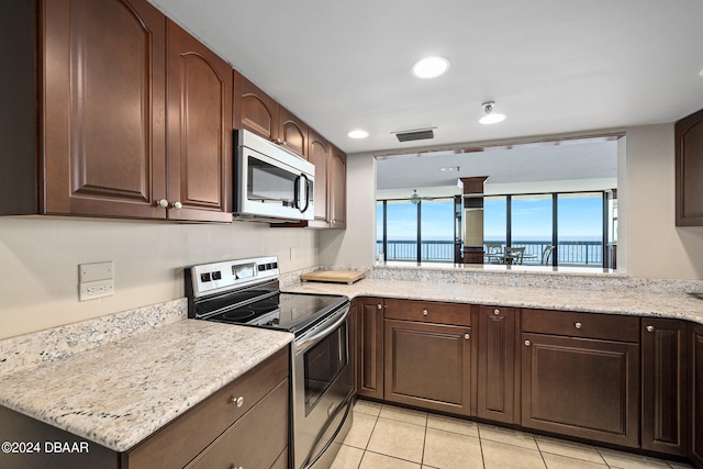 kitchen featuring kitchen peninsula, light tile patterned flooring, light stone counters, and appliances with stainless steel finishes